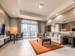 a living room with a couch and a table at Grand Mercure Bangkok Asoke Residence in Bangkok