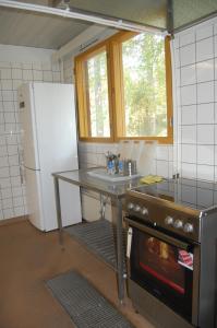 Kuhasensaari Lomakeskus في Lemi: مطبخ مع طاولة ومغسلة وثلاجة