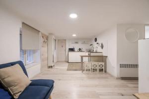 COSY COTTAGE - Cheerful Apartment in the Center في بودابست: غرفة معيشة مع أريكة زرقاء ومطبخ