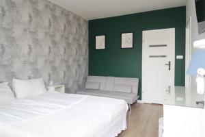 a bedroom with a white bed and a green wall at La Mare in Władysławowo