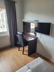 a desk with a monitor and a chair in a room at Highway Hotel in Härnösand