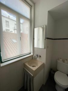 a bathroom with a sink and a window and a toilet at Casa da Carqueja in Coimbra
