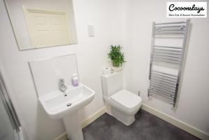 Cocooonstays Short Lets & Accommodation Slough في سلاو: حمام ابيض مع مرحاض ومغسلة