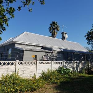 een wit huis met een hek en een palmboom bij 13 Maitland Road in Koning Willemstad