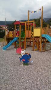a young boy sitting on a playset in a playground at Apartman Sofija in Plužine