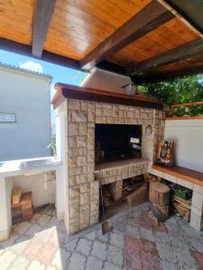 a patio with a stone fireplace with a wooden roof at Apartment Miric in Crikvenica