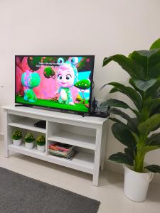 TV de pantalla plana en un centro de entretenimiento blanco en Homestay KLIA Core Soho Suites, en Sepang