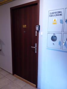 una puerta de madera en una habitación con un cartel en la pared en Tulip Jagiellonska - poddasze bez windy, en Szczecin