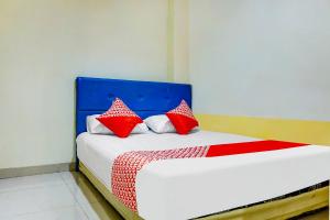 a bed with red and white pillows on it at OYO 91182 Kos'ta Homestay Makassar in Makassar