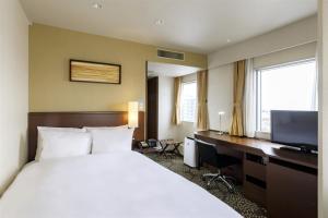 a hotel room with a large bed and a television at ANA Holiday Inn Kanazawa Sky, an IHG Hotel in Kanazawa