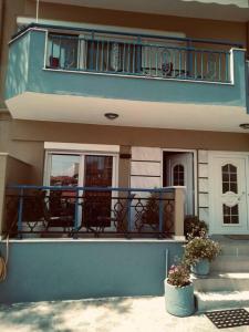 a blue house with a balcony and two potted plants at Minimal & cozy studio ΜΕ ΔΩΡΕΑΝ ΧΩΡΟ ΣΤΑΘΜΕΥΣΗΣ in Kavala
