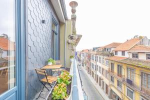 einen Balkon mit einem Tisch und Stühlen sowie Straßenblick in der Unterkunft 12 Sweet Caroline in Porto