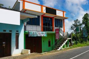 um edifício colorido com uma varanda ao lado de uma rua em OYO Homes 91132 Desa Wisata Kalipucang em Nongkejajar