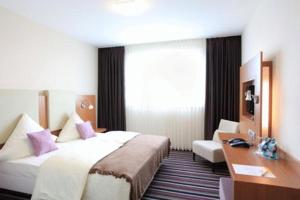 ヒルポルトシュタインにあるQualitel Hilpoltsteinのベッドとデスクが備わるホテルルームです。