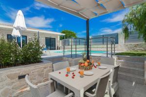 a patio with a table and chairs and a pool at Lea Villa - Brand New Modern Villa! in Zakynthos Town