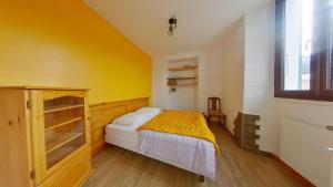 1 dormitorio con cama y pared amarilla en Appartement entier T4 à Jausiers, en Jausiers