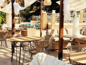 an outdoor patio with tables and chairs and umbrellas at Avra Sunset Sea View Liapades in Liapades