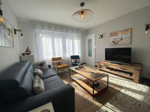 a living room with a blue couch and a television at Du gite dans les Toiles in Wimereux