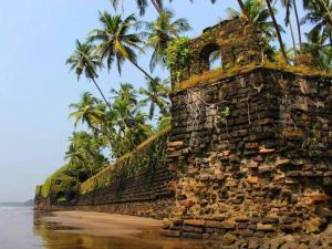 an old stone wall on the beach with palm trees at Parvati Niwas Homestay -Nearby Revdanda Beach & Fort - WiFi available in Alibaug