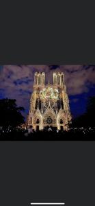 um edifício iluminado com luzes acesas à noite em Hôtel De La Cathédrale em Reims