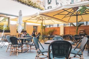 un patio al aire libre con mesas, sillas y sombrillas en Magnolia Napoli en Nápoles