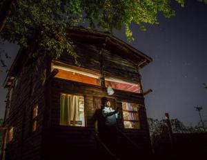 un hombre parado en una ventana de una casa por la noche en Cabaña La Triada, Grupo Cabaña La Triada en Río Ceballos