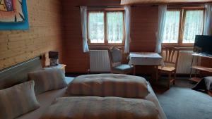 a room with two beds and a table and windows at Gasthaus Montafonerhüsli in Sankt Gallenkirch