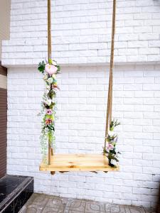 a wooden swing hanging from a white brick wall with flowers at Hotel Sao Khuê in Sa Ðéc
