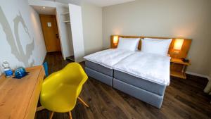 a hotel room with a bed and a yellow chair at Hotel Bellevue Kriens in Luzern