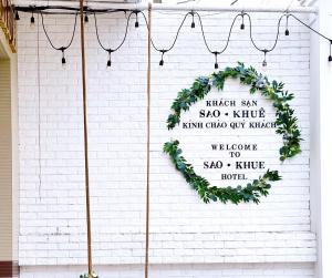 a wreath on a white brick wall with a sign at Hotel Sao Khuê in Sa Ðéc