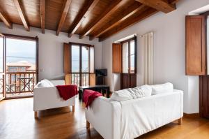 a living room with two white couches and a balcony at Vivienda Vacacional Leo in Andrín