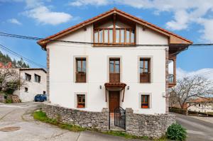 a white house with a stone wall at Vivienda Vacacional Leo in Andrín