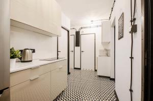 uma cozinha com armários brancos e piso em azulejo preto e branco em Pomorska Rooms em Lódź