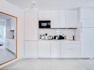 uma cozinha branca com armários brancos e um espelho em limehome Madrid Calle Ave María - Digital Access em Madri