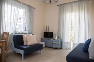 sala de estar con silla azul y TV en Blue Theros Apartments, en Paralia Dionisiou