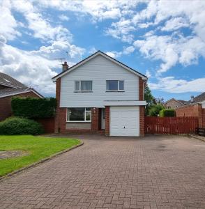 a white house with a garage on a driveway at Rozelle Villa in Ayr