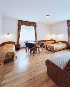 a hotel room with two beds and a table and chairs at Marel-Apartments U SOWY- Park- Polanica Zdrój in Polanica-Zdrój