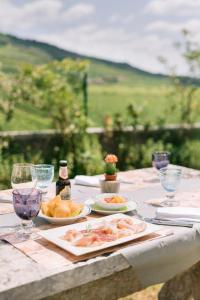 BACCO D'ORO Wine & Relais في Mezzane di Sotto: طاولة مع أطباق من الطعام وكؤوس النبيذ