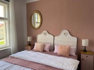 HartmaniceにあるApartment Stará Poštaのベッドルーム1室(ピンクの枕と鏡付きのベッド1台付)