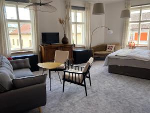 ein Schlafzimmer mit einem Bett, einem Sofa und Stühlen in der Unterkunft Apartment Stará Pošta in Hartmanice