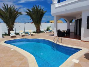 a swimming pool in a resort with the beach in the background at Villa Real Oliva in Corralejo