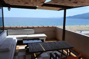 een balkon met een tafel en een bank en het strand bij Big Dino's Galini in Nea Vrasna