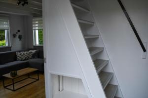 a stairway leading to a living room with a couch at Naar de kust in Hollum