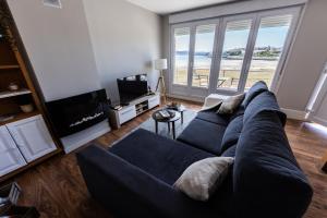 Una sala de estar con un sofá azul y una ventana grande. en Apartamentos Playa de Camariñas, en Camariñas