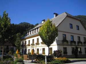 ein großes weißes Gebäude mit einem Baum davor in der Unterkunft Gasthof Rüscher in Donnersbach