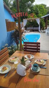 a table with plates of food next to a swimming pool at pousada corais de abrolhos in Caravelas