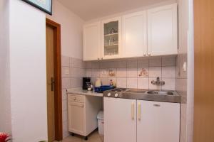 a kitchen with white cabinets and a sink at Apartments City Center Dekanić in Krk