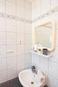 La salle de bains blanche est pourvue d'un lavabo et d'un miroir. dans l'établissement Apartments City Center Dekanić, à Krk
