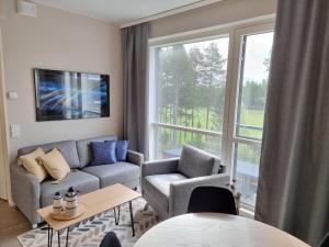 ein Wohnzimmer mit einem Sofa, Stühlen und einem Fenster in der Unterkunft Apartment Marinan Portti B37 kaksio Kalajoki in Kalajoki