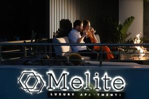 a man and woman sitting on a couch playing a saxophone at Melite Luxury Rooms & Apartments in Paliouri